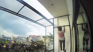 Una persona penzola da una barra per trazioni su un balcone con vista sulla città.