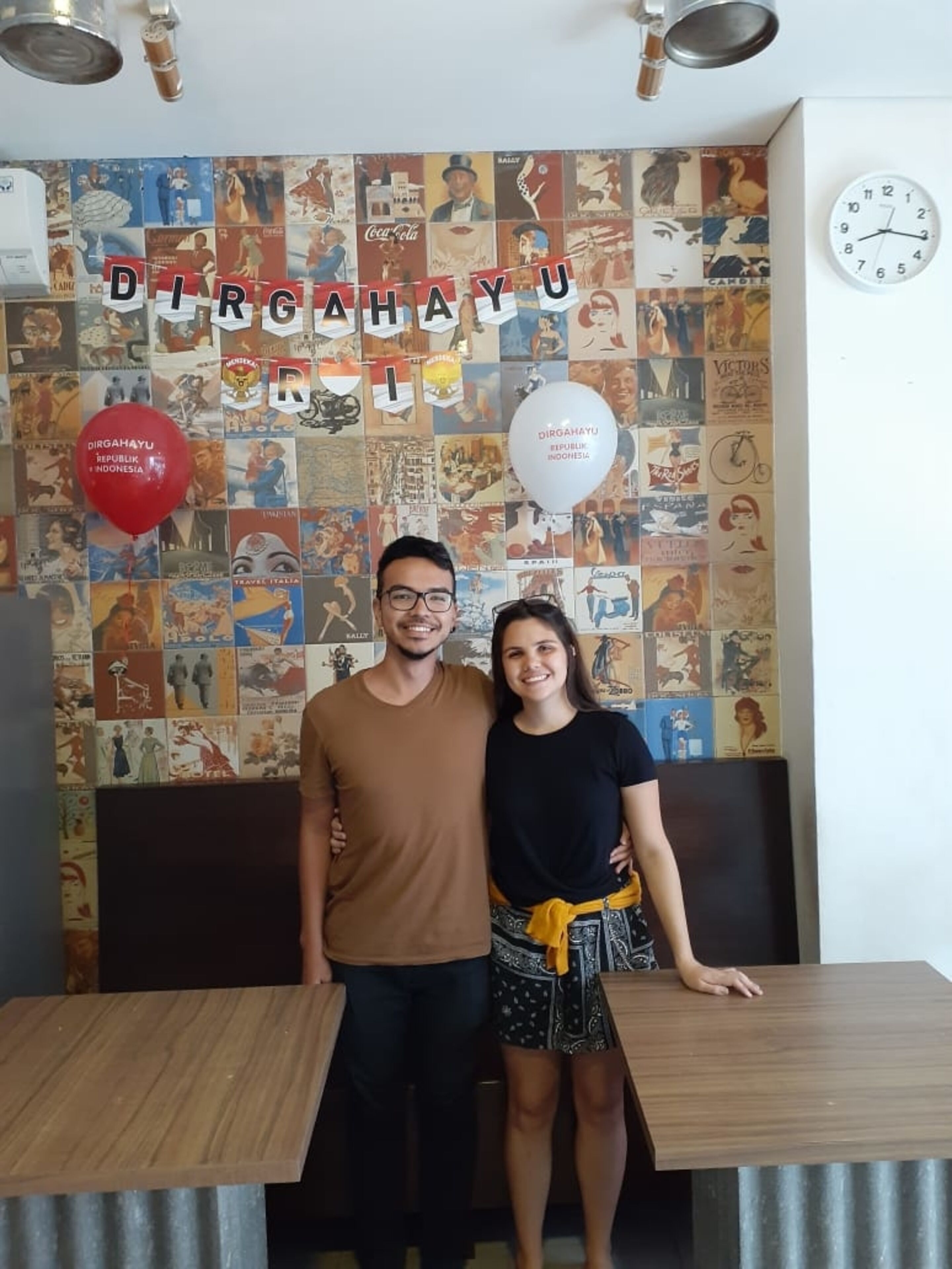 Un'area pranzo con una parete decorata da manifesti di viaggio vintage e un orologio a parete.