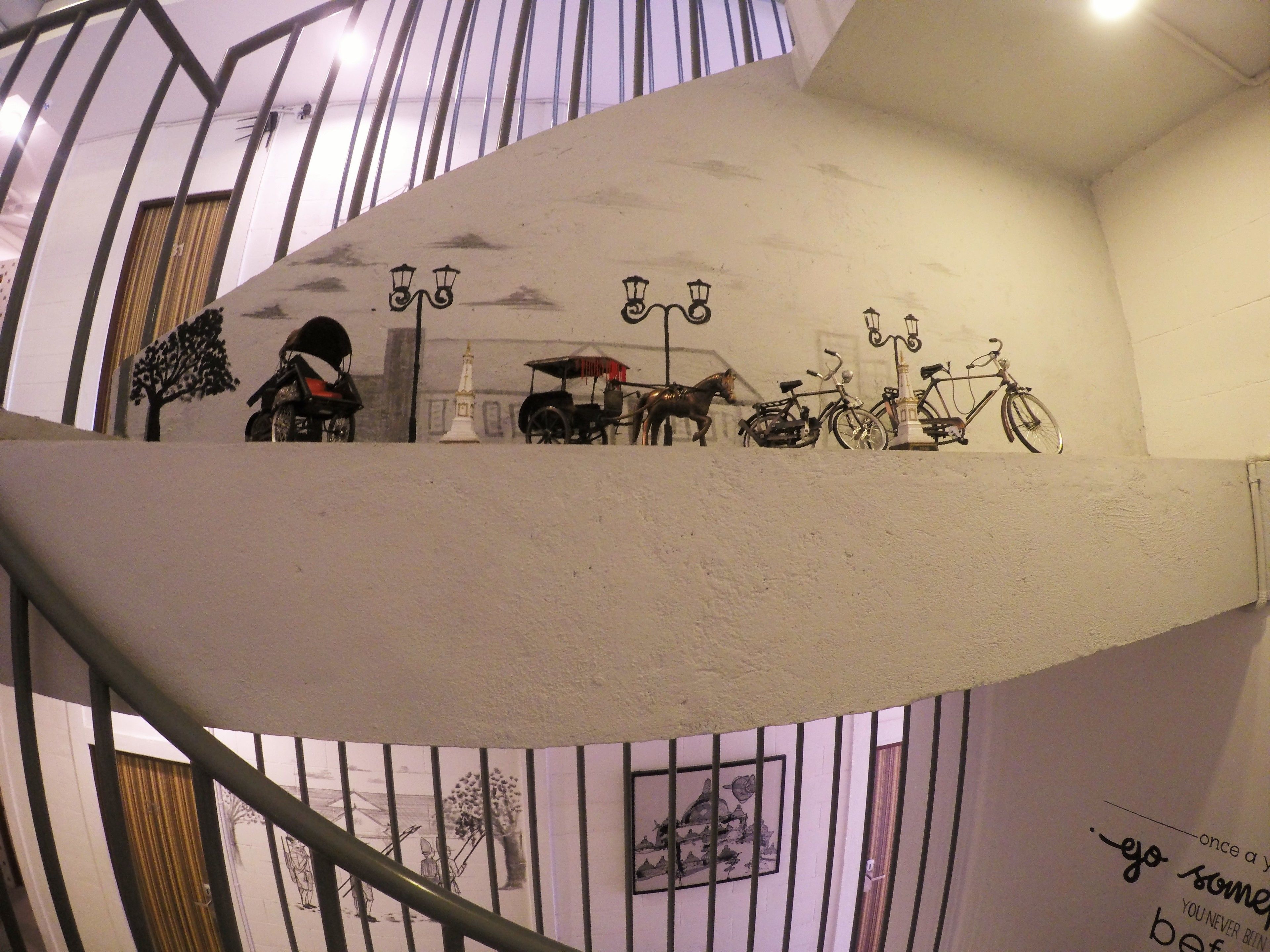 Una scala a chiocciola con un espositore a parete che mostra biciclette d'epoca e una piccola torre bianca.