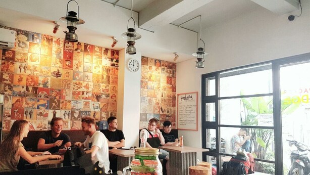 Un caffè con una parete di manifesti d'epoca, una sveglia e un'ampia finestra vista esterna.