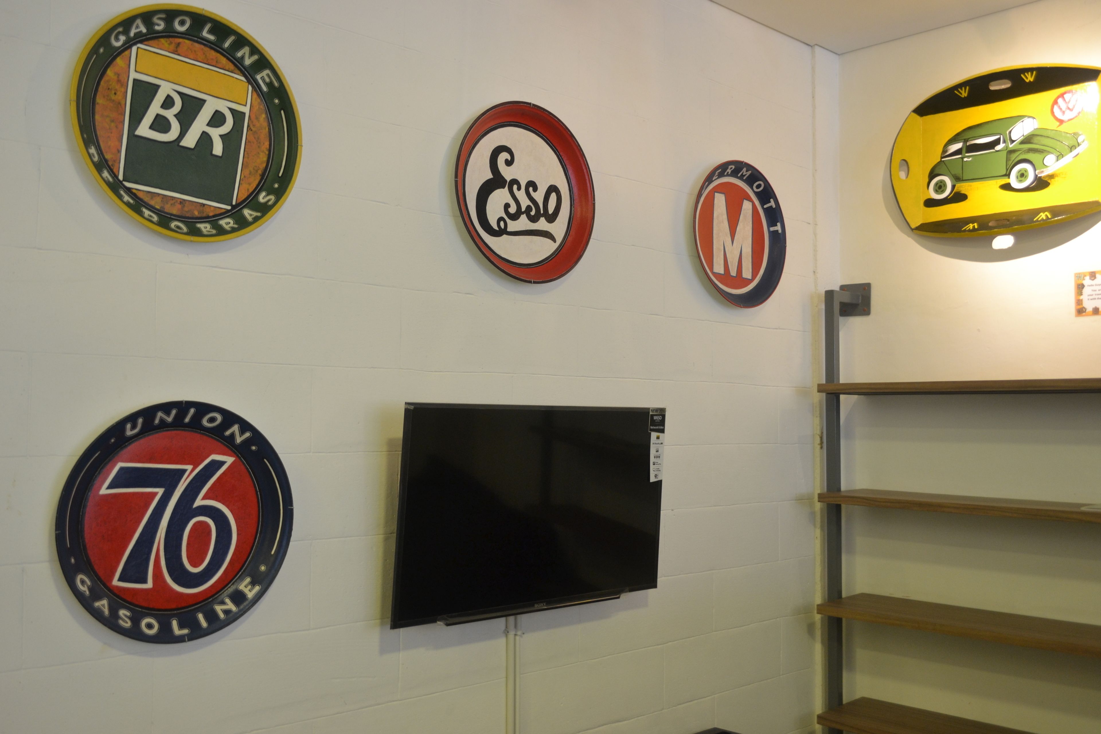 A wall with vintage gas station signs and a television.