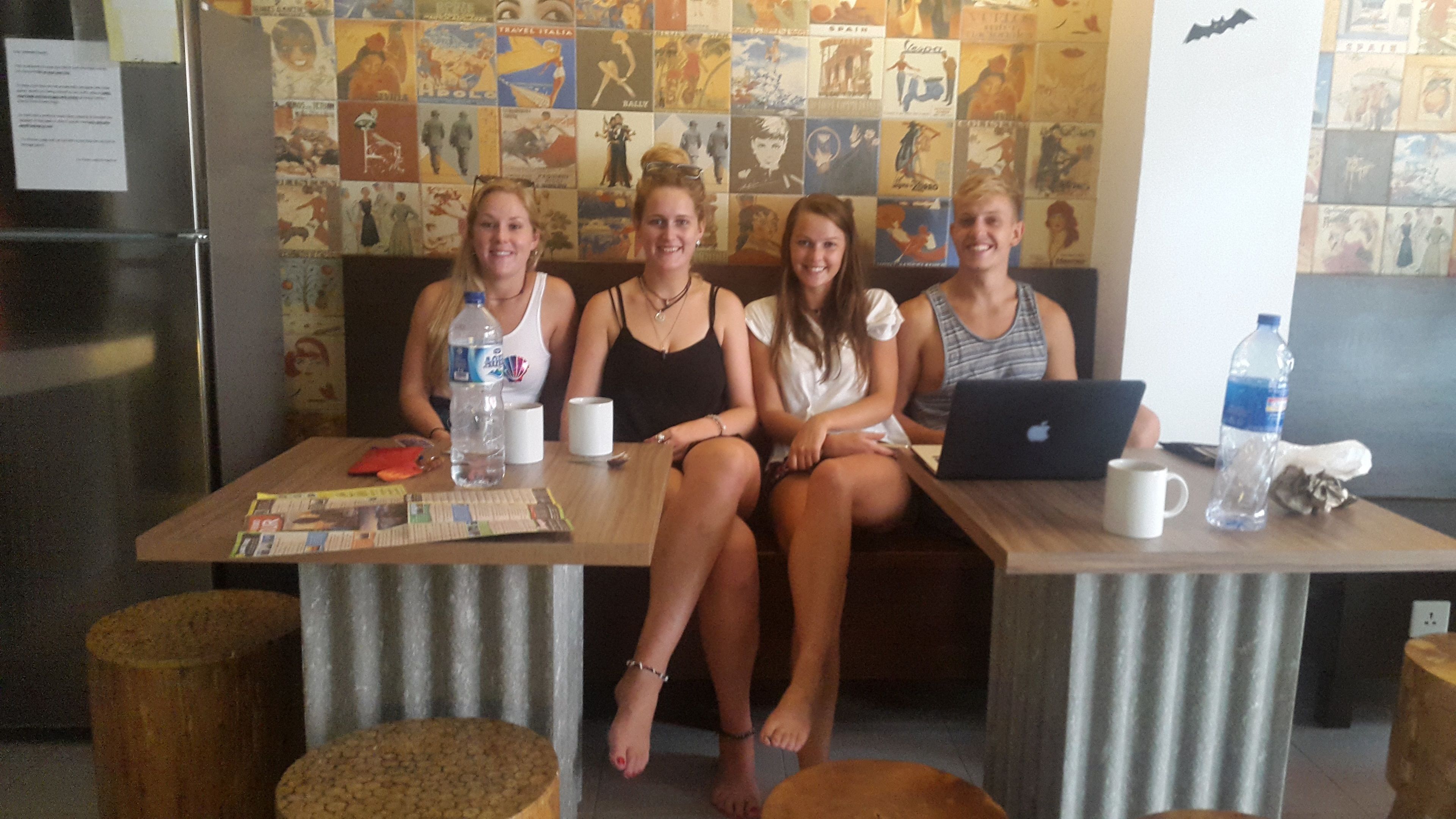 A group of people seated at a wooden table with a laptop, water bottles, and a map.