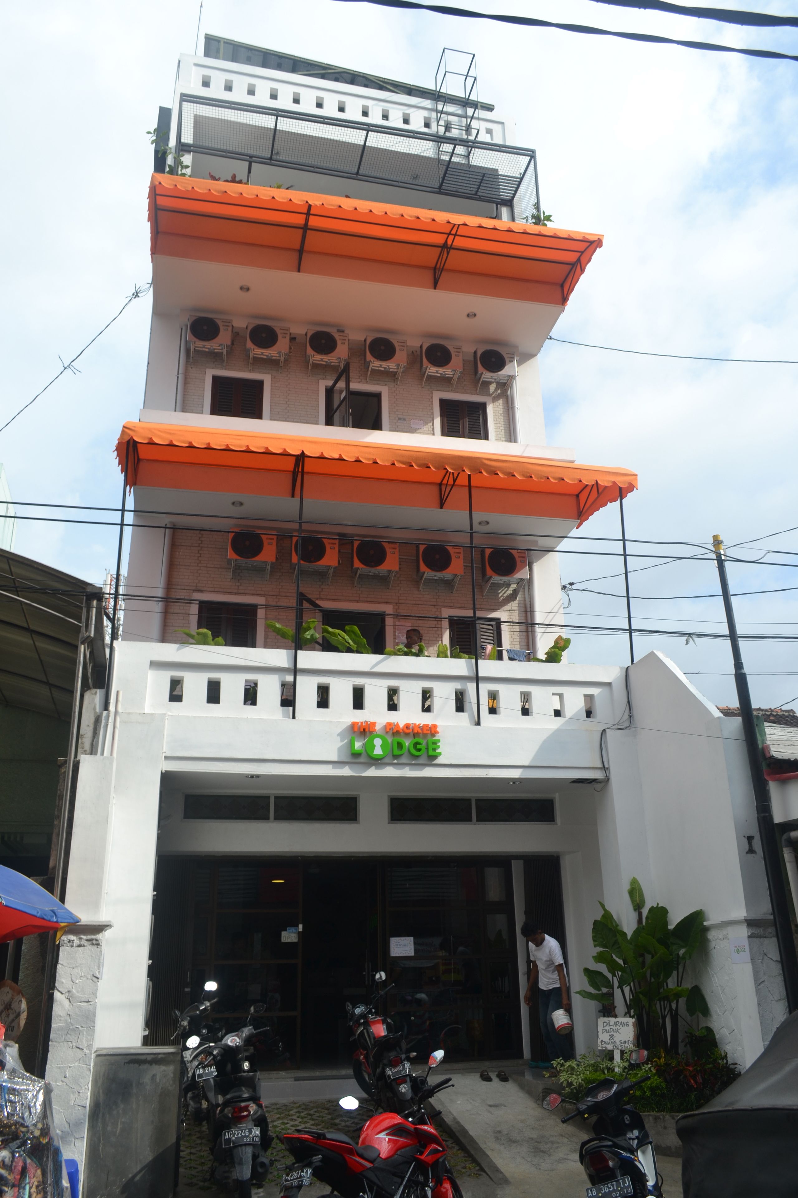 A multi-story building with a sign reading "The Lodge." There are several motorcycles parked in front, and a person is seen entering the building.