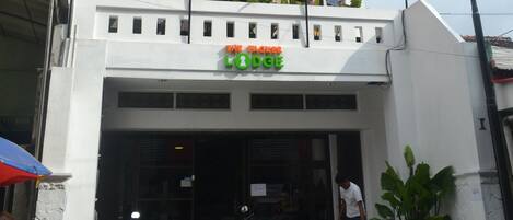 A multi-story building with a sign reading "The Lodge." There are several motorcycles parked in front, and a person is seen entering the building.