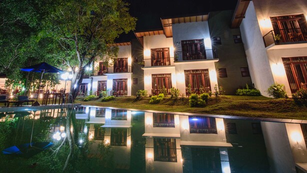 A modern hotel with a pool, multiple balconies, and outdoor seating areas. - Hotel Wewa Addara (Sigiriya)