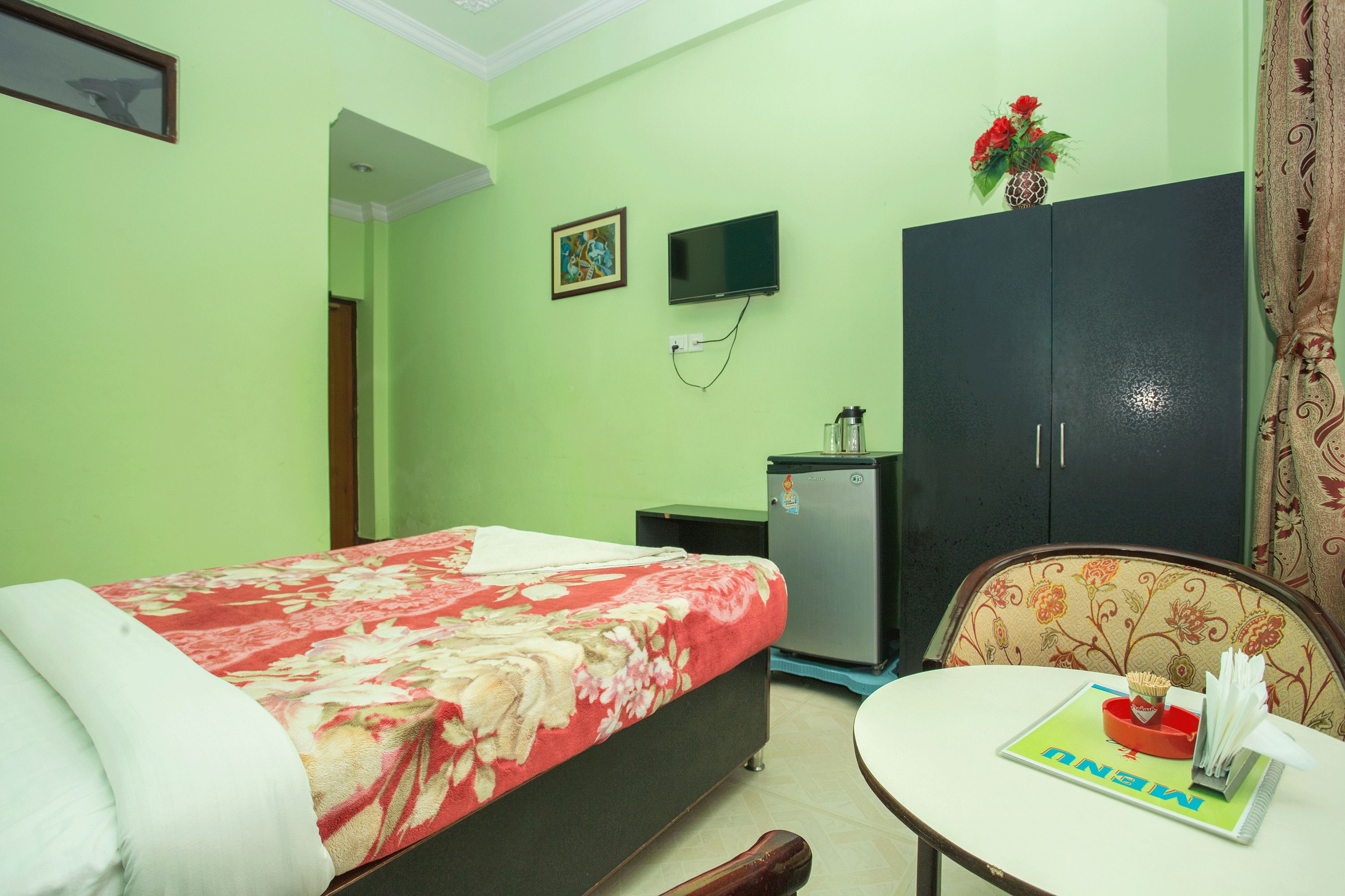 Une chambre d’hôtel comprenant un lit, une télévision, une armoire, une petite table et une chaise.