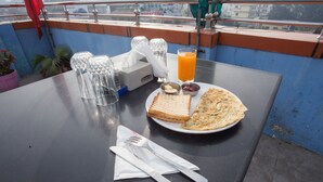 A table with a plate of food, a glass of orange juice, and a tissue box. - Hotel Jalsa (Dhangadhi)