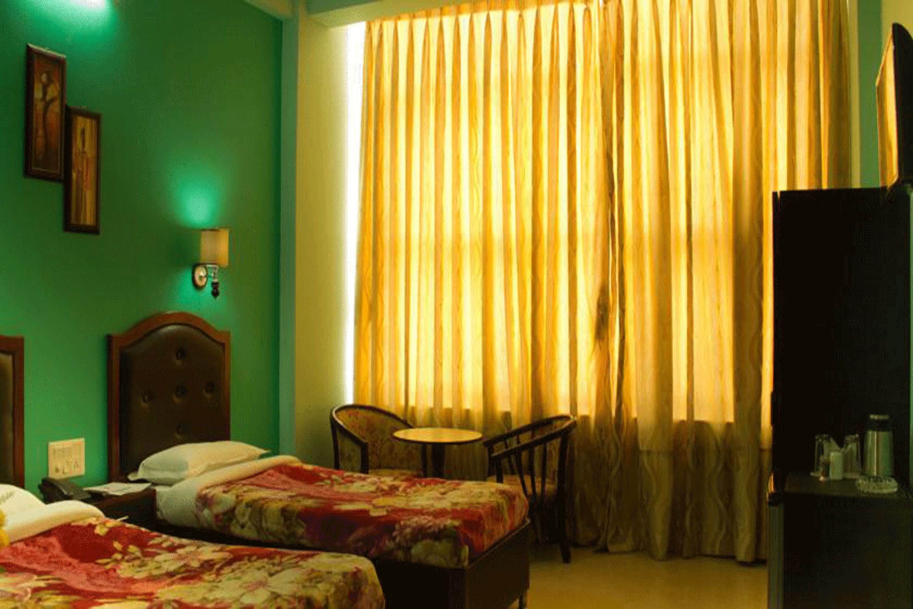 A hotel room with two beds, a small table, a chair, and a television.