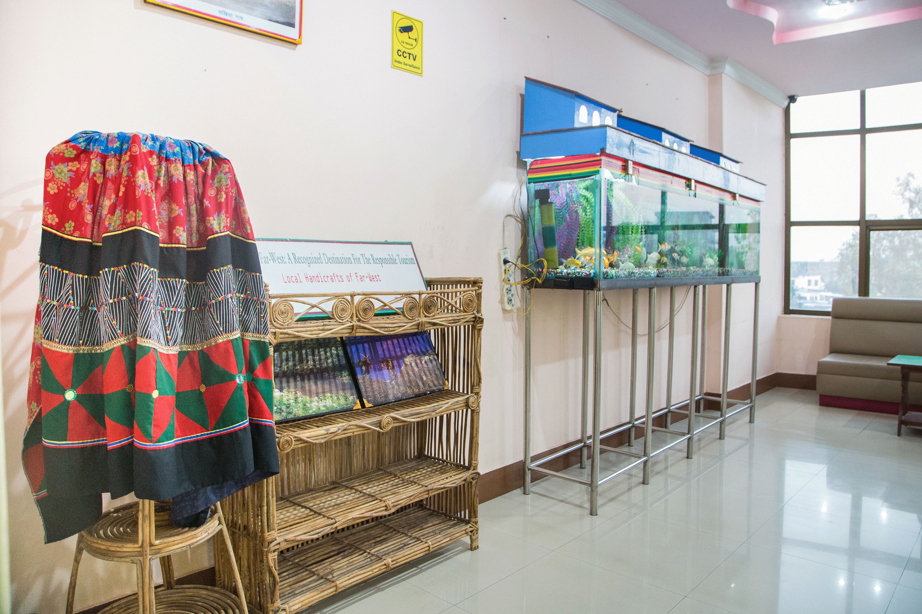 A room with a decorative wall hanging, a fish tank, and a sign about local handicrafts.