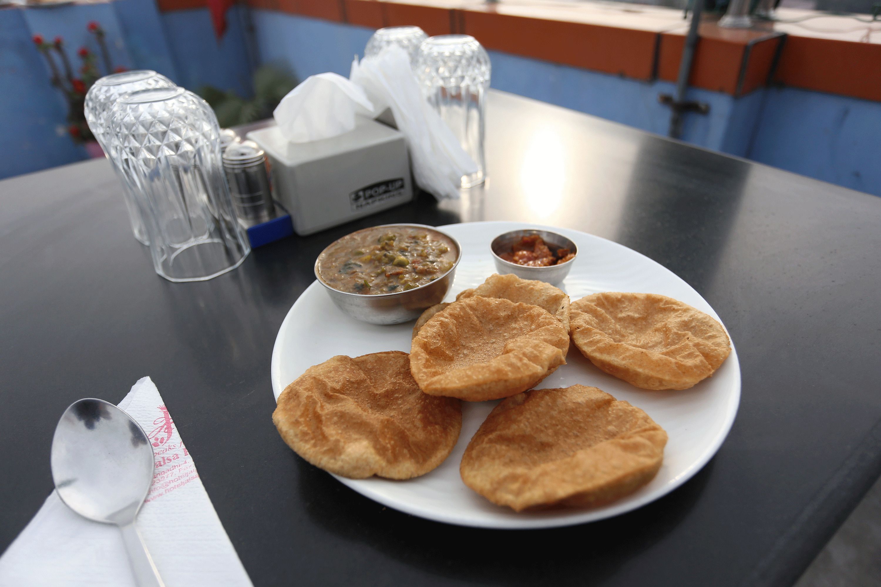 Un plato con varios alimentos fritos y dos recipientes pequeños de salsas para mojar sobre una mesa.