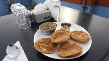 Un plato con varios alimentos fritos y dos recipientes pequeños de salsas para mojar sobre una mesa.