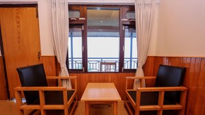 A wooden room with a table and two chairs, a window with curtains, and a view of the outside balcony. - Dhaulagiri View Hotel (Pokhara)