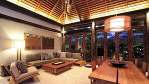 A spacious living area with a wooden ceiling, a sofa set, a coffee table, and a dining table with chairs. - Villa Suar Drupadi (Seminyak)