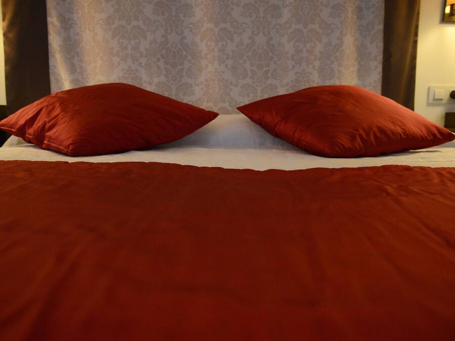 Una cama con una colcha y dos almohadas rojas.