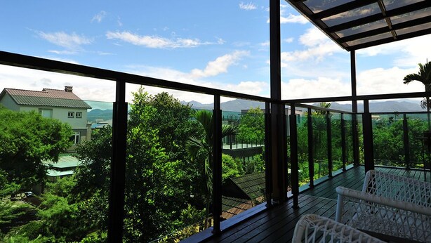 Un balcón con vistas a un paisaje verde exuberante y montañas distantes.