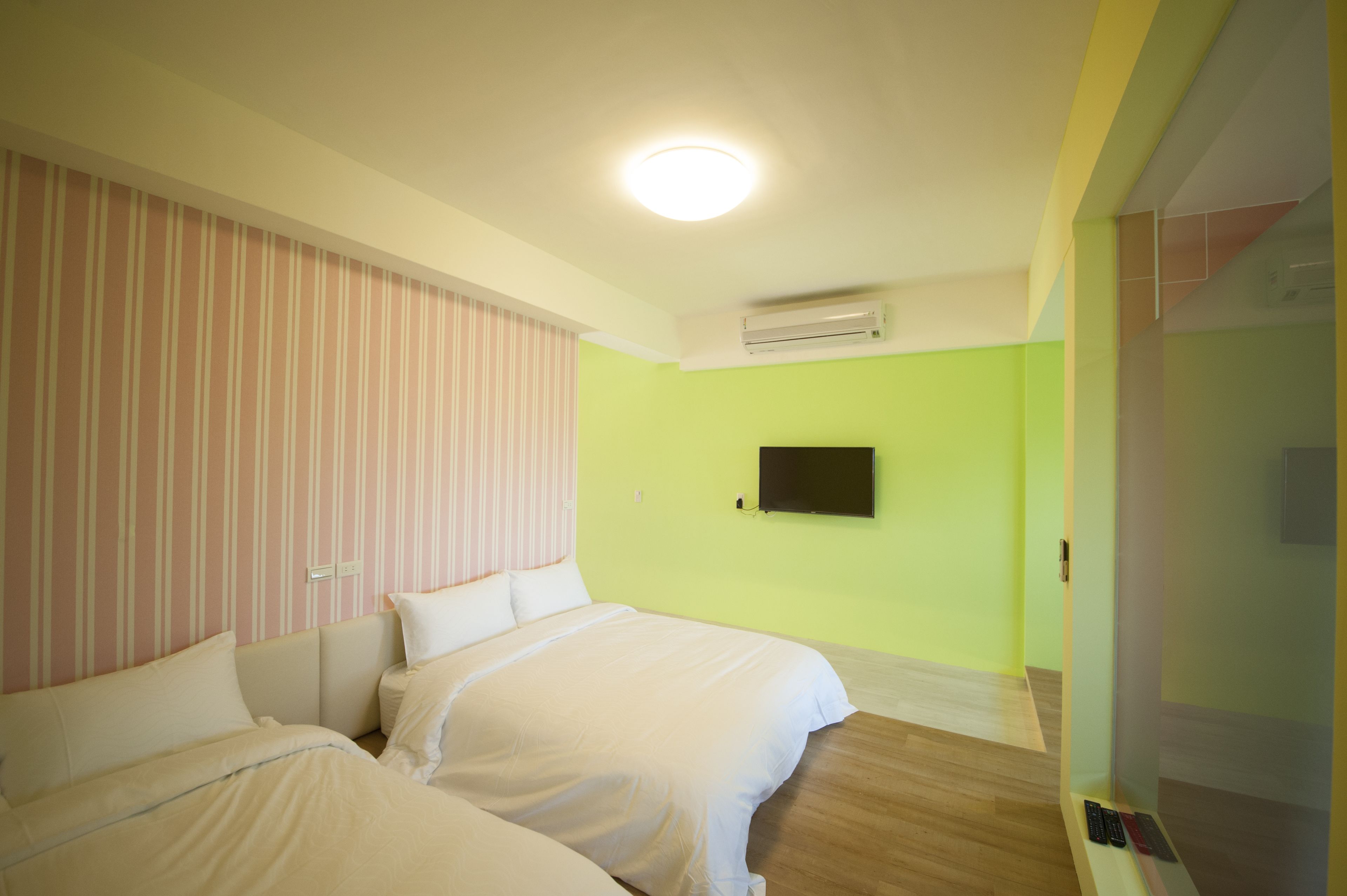 Habitación con dos camas, un televisor de pantalla plana en la pared y un equipo de aire acondicionado.
