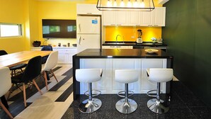 Una cocina moderna con armarios blancos, encimera negra y una isla central con taburetes de bar.