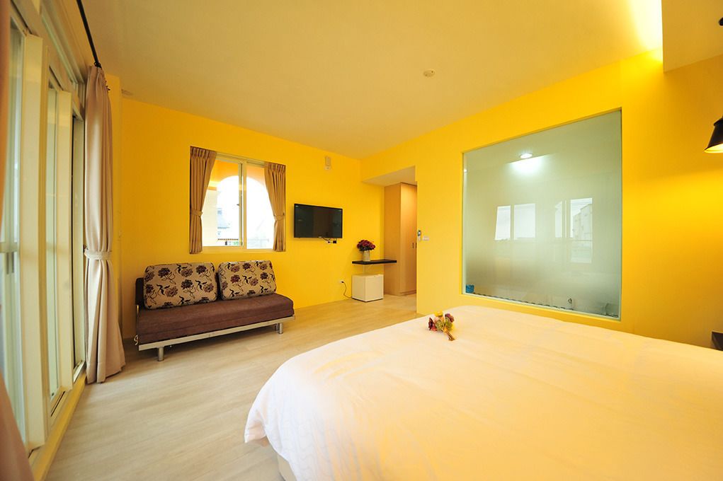 Una habitación con cama, sofá, televisión y espejo.
