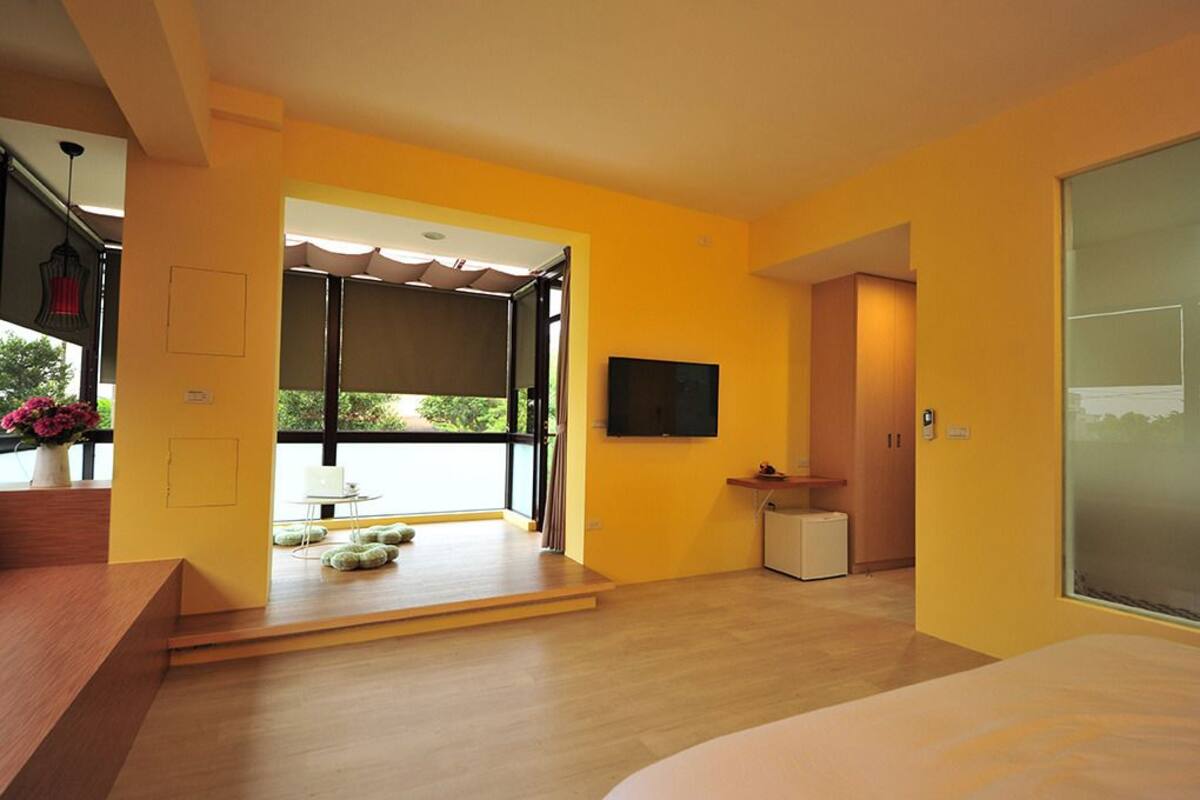 A modern room with a large window, a flat-screen TV, a small table, and a sofa.