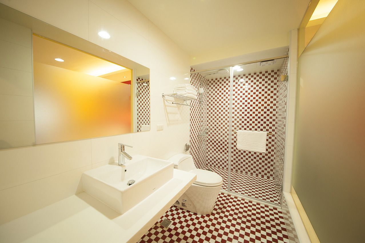 Een moderne badkamer met een zwart-wit betegelde vloer, een witte wastafel en een douchecabine van glas.