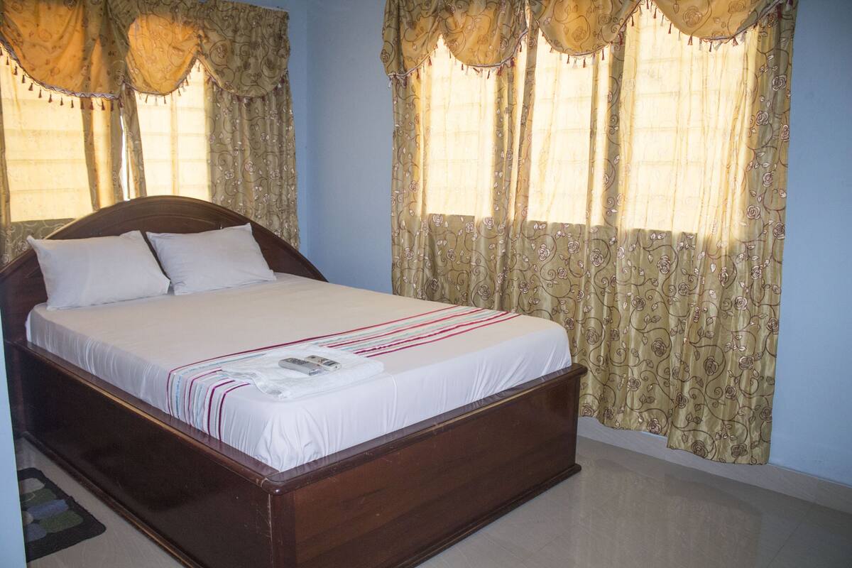 A bedroom with a wooden bed, white bedding, and patterned curtains.