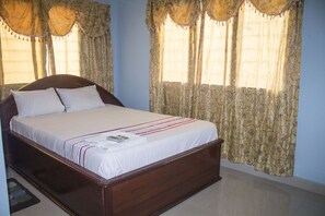 Un dormitorio con cama de madera, ropa de cama blanca y cortinas estampadas.