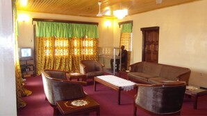 A living room with a sofa, two armchairs, a coffee table, a television, and curtains. - Adinkra Lodge (Accra)