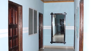 A hallway with wooden doors, a mirror, and a ceiling light. - Adinkra Lodge (Accra)