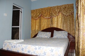 Un dormitorio con una cama, cabecera de madera y una ventana con cortinas.