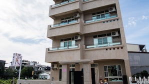 Un edificio de varios pisos con balcones y ventanas grandes, que presenta una fachada plana y una entrada con portón.