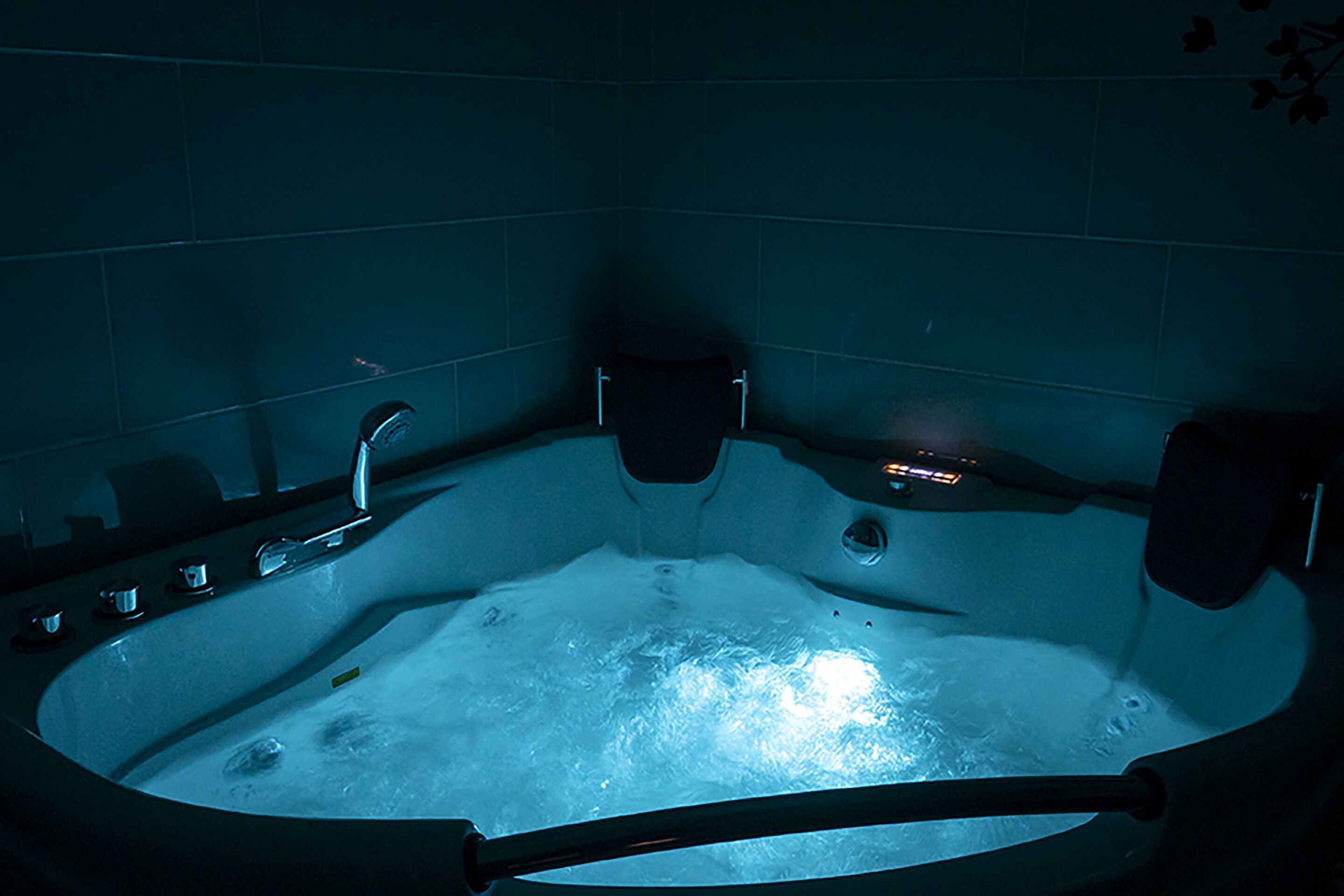 A hot tub with a visible water jet, a control panel, and a seating area.