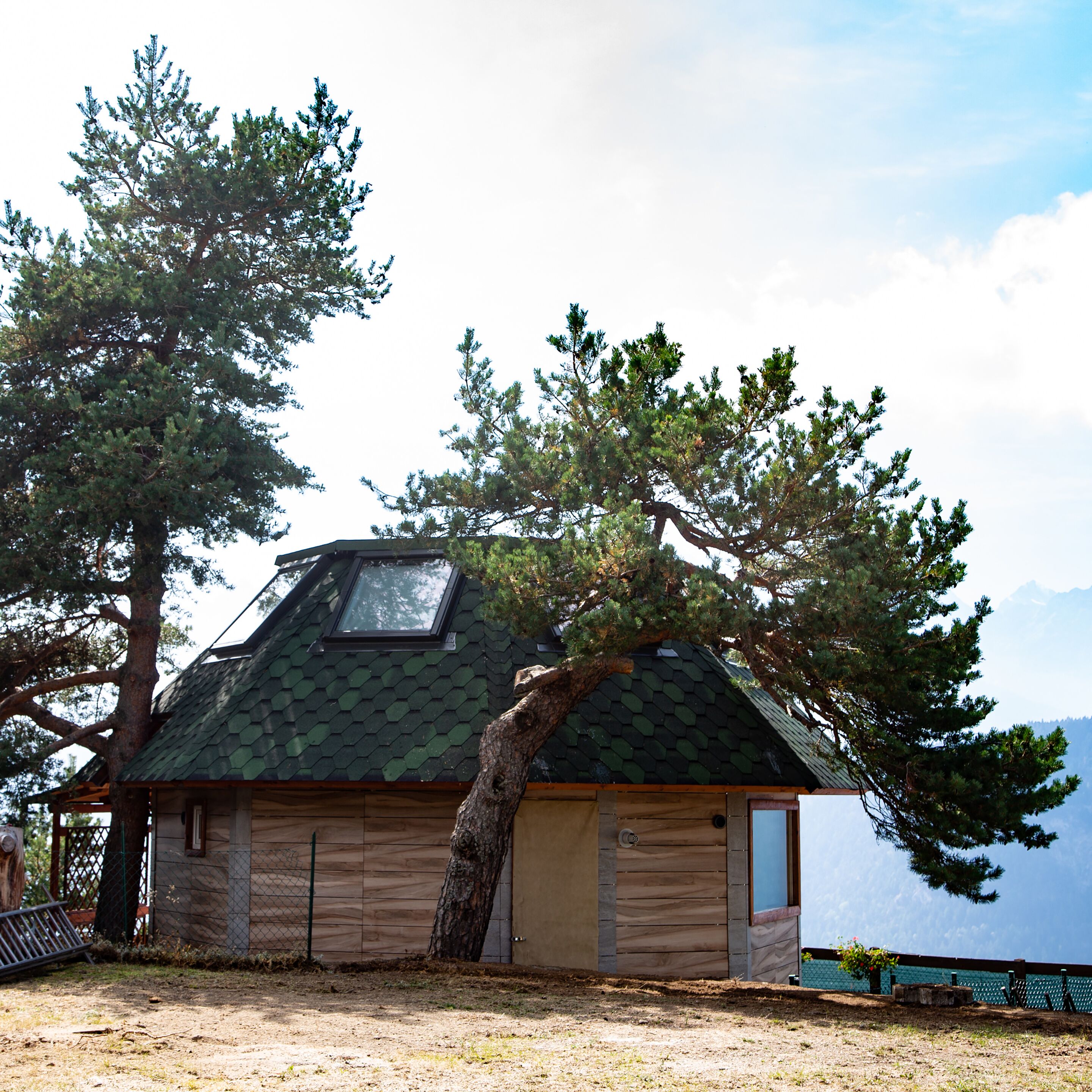A cabin with a sloped roof, a skylight, and a wooden exterior.