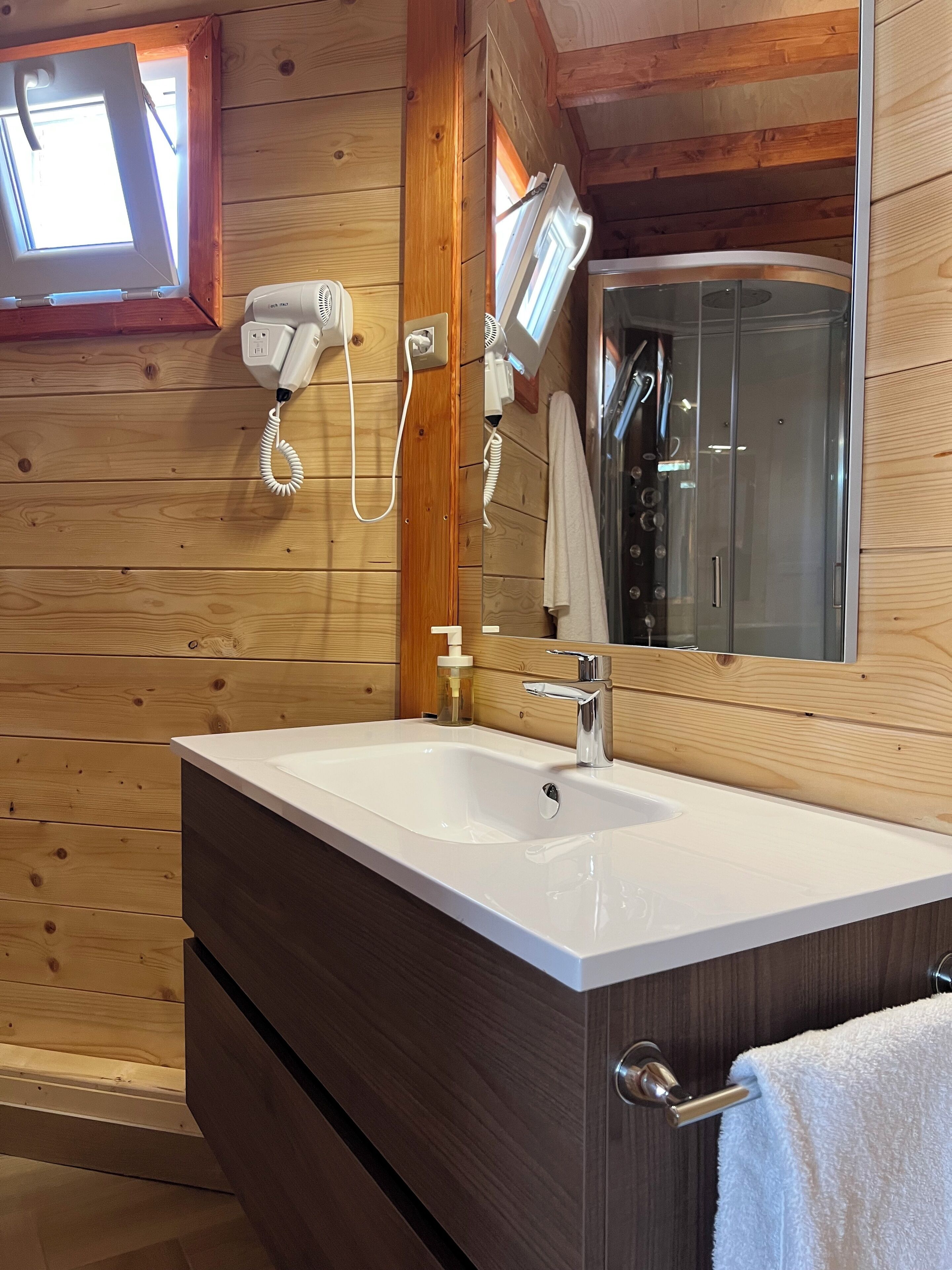A wooden cabin bathroom with a white sink, a mirror, and a towel rack.