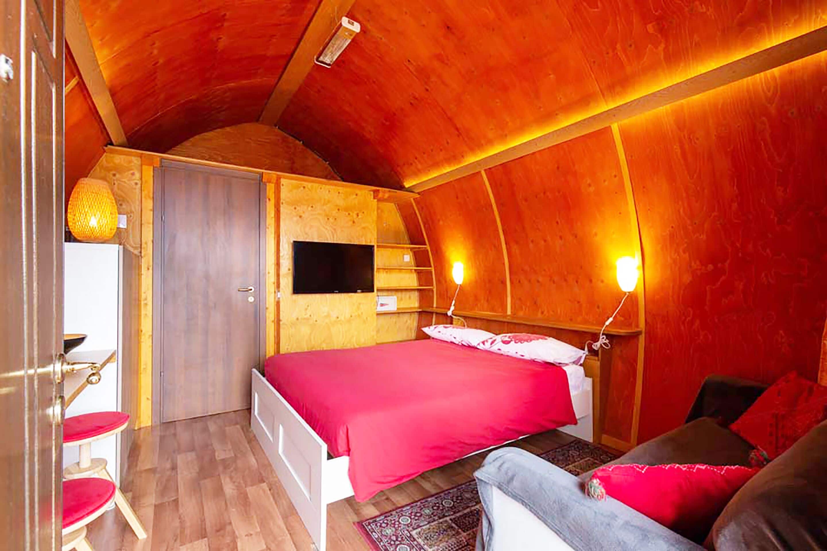 A cozy, wooden-themed bedroom with a bed, a desk, and a chair.