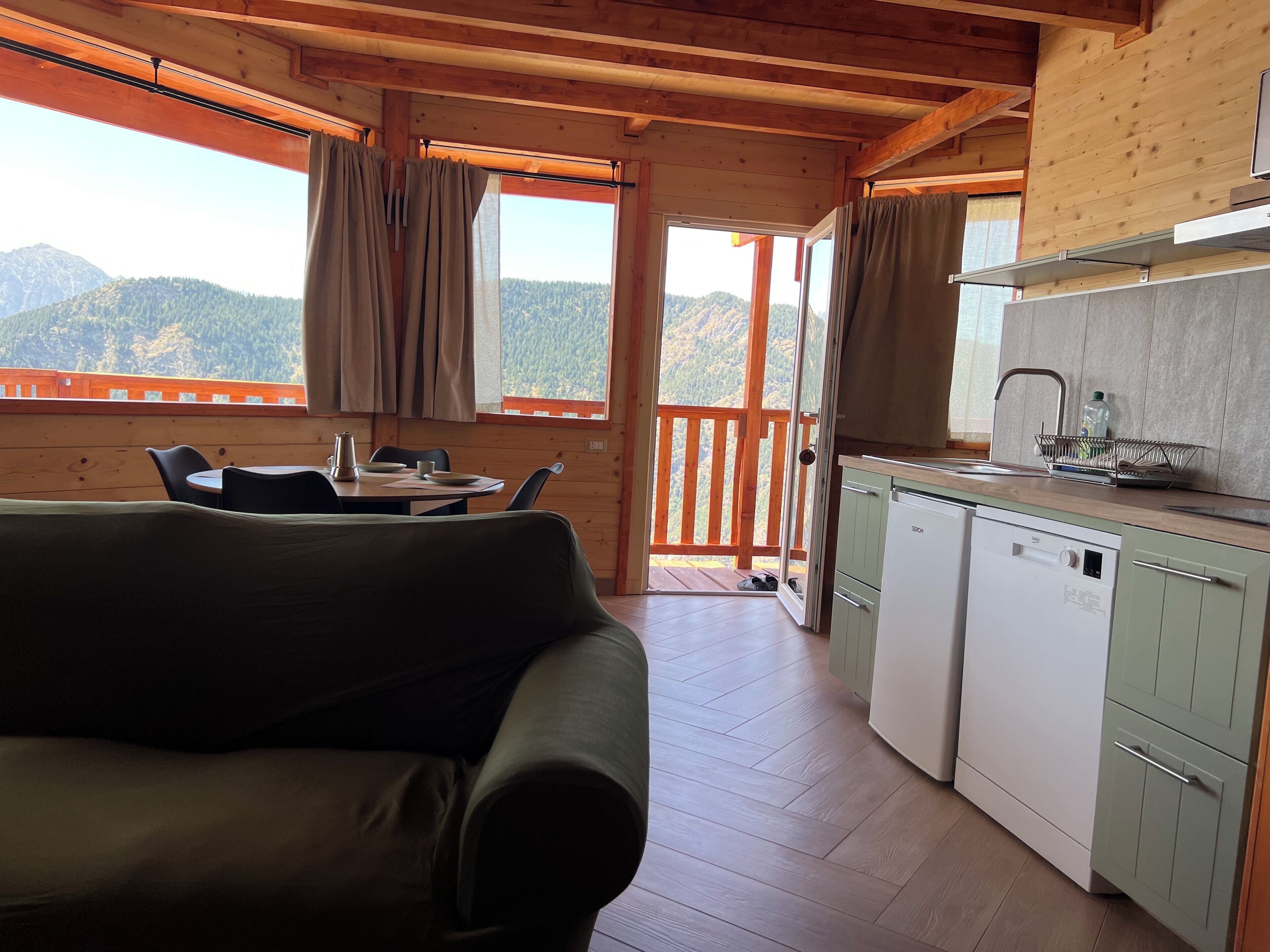 A cozy cabin with a dining area, a kitchenette, and a balcony with a mountain view.