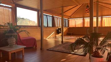 Una habitación amplia con pisos de madera, ventanas grandes con cortinas, una chimenea y varios alfombras.