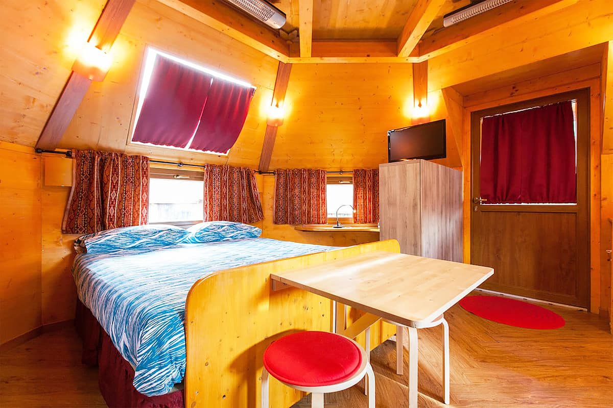 Una habitación acogedora tipo cabaña con cama, una mesita y televisor.
