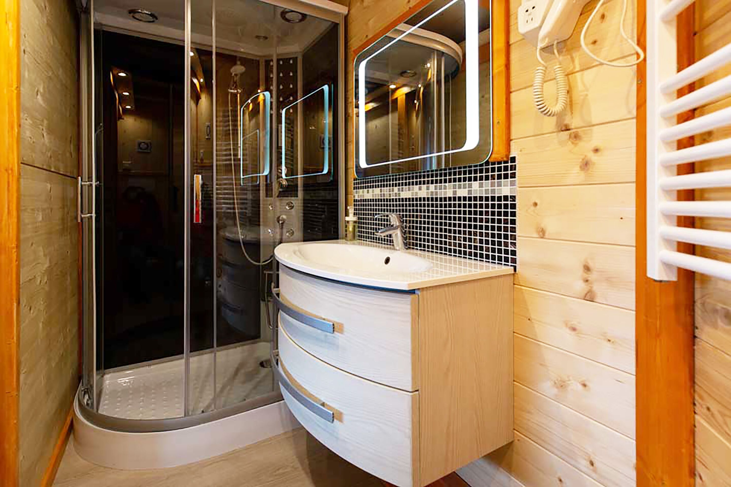 Une salle de bain moderne avec une douche à parois de verre, un meuble-lavabo en bois et un miroir au-dessus du meuble.