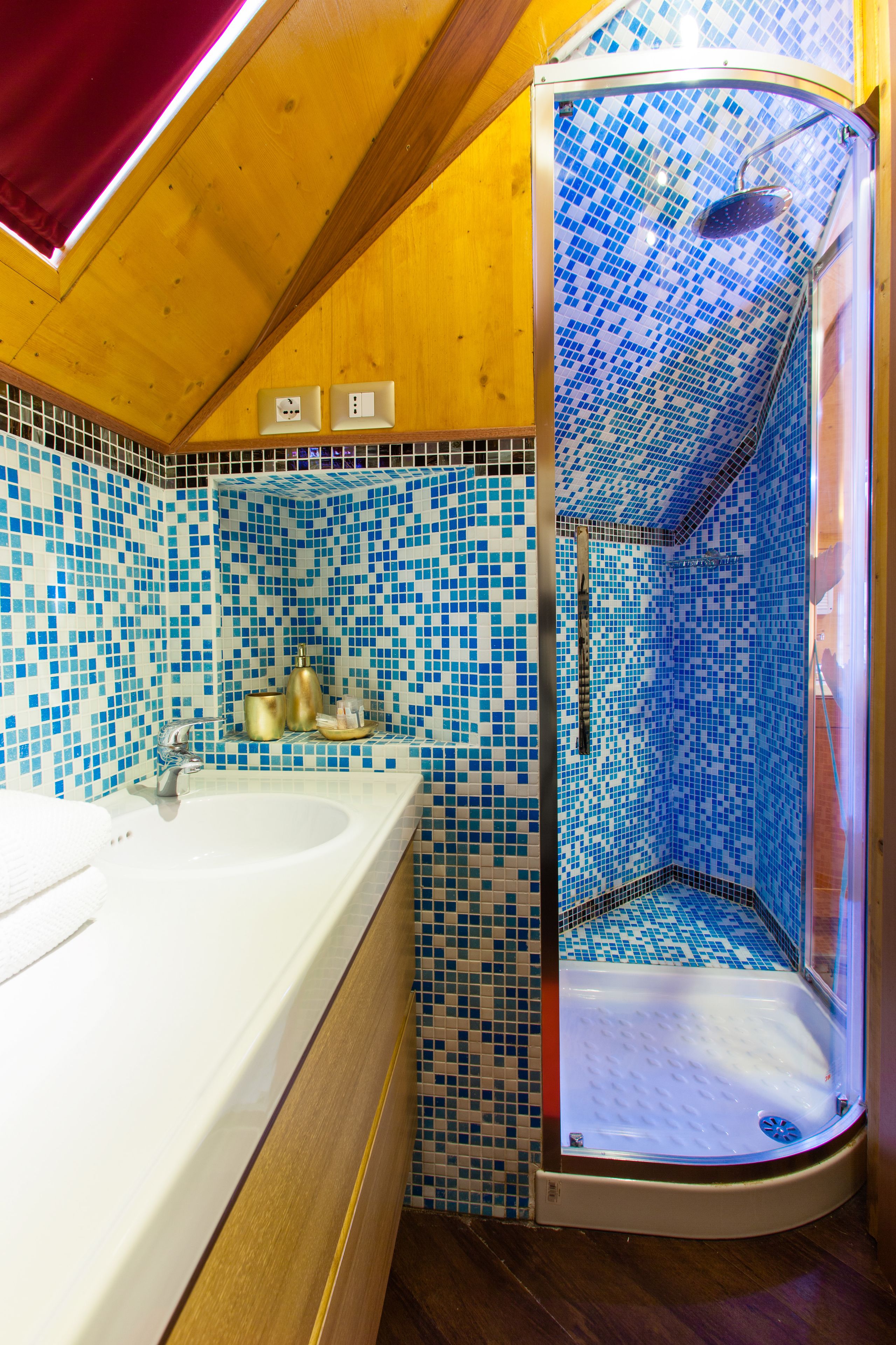 A bathroom with a mosaic tile wall, a white sink, and a shower enclosure.