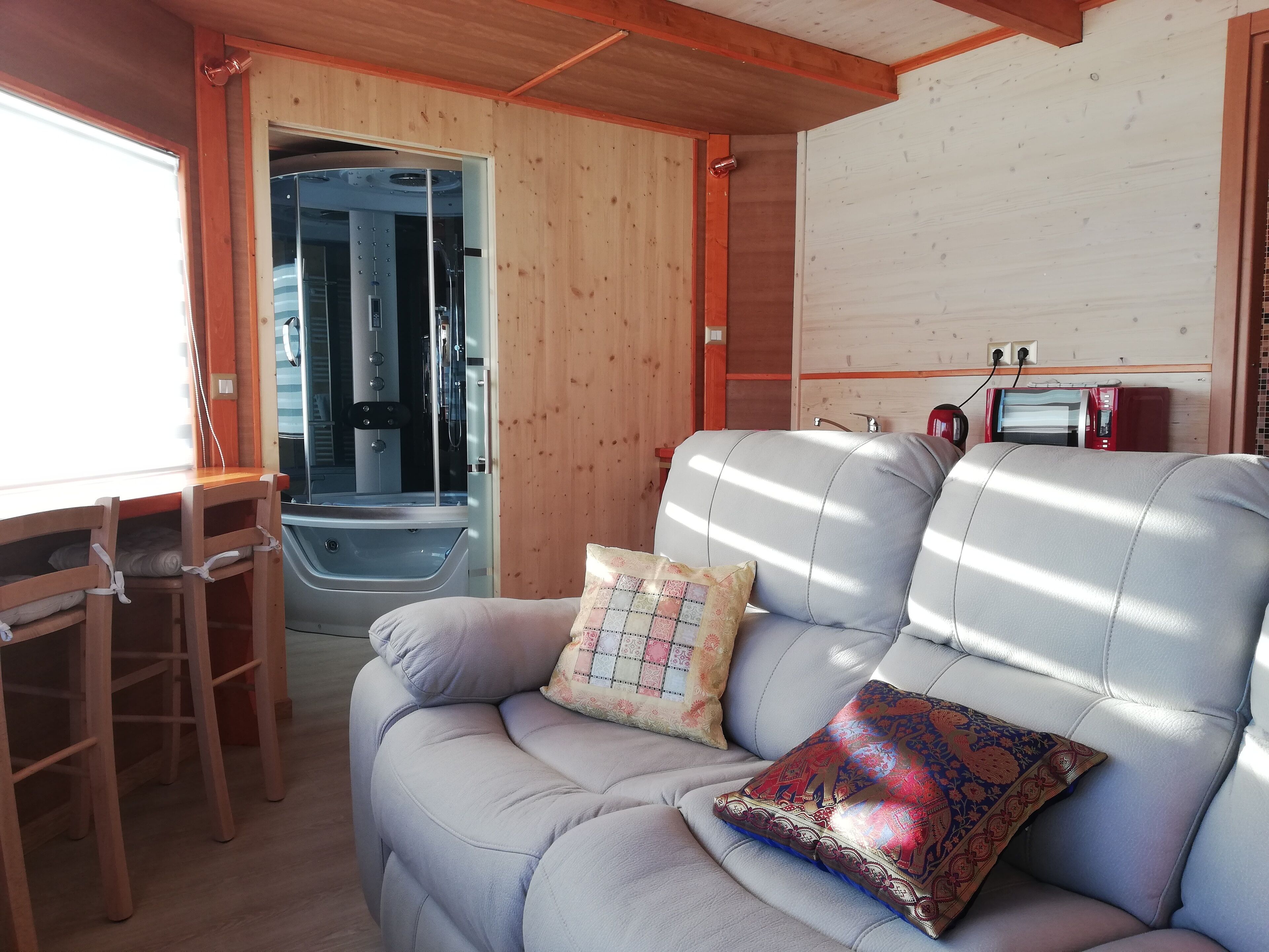 Indretning i en hyggelig hytte med sofa, et lille bord og et bruseområde.