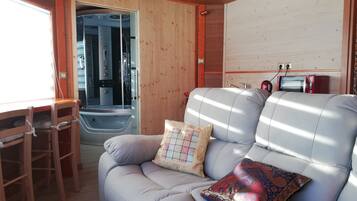 Indretning i en hyggelig hytte med sofa, et lille bord og et bruseområde.
