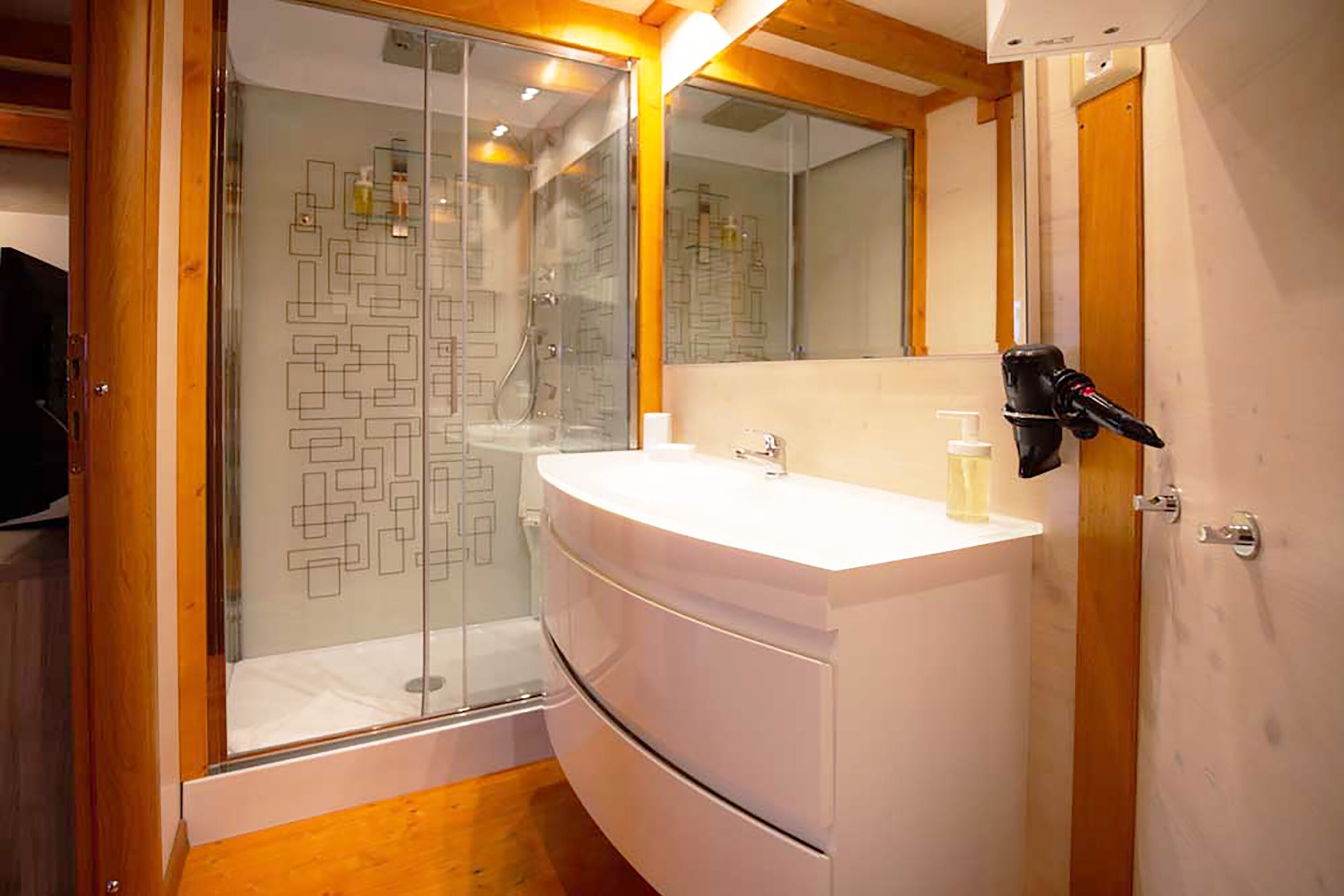 A modern bathroom with a glass-enclosed shower, a white vanity, and a mirror above the sink.