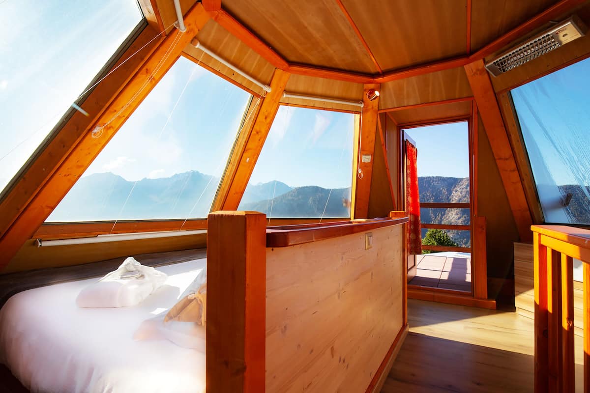 Una habitación espaciosa con techos altos, vigas de madera y grandes ventanales con vistas a la montaña.