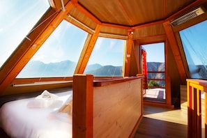 A high-ceilinged room with wooden beams and large windows offering mountain views.