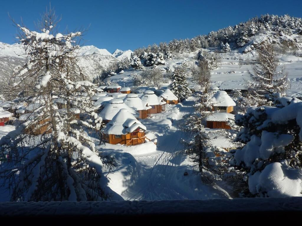 Un pueblo cubierto de nieve con casas de madera y árboles.