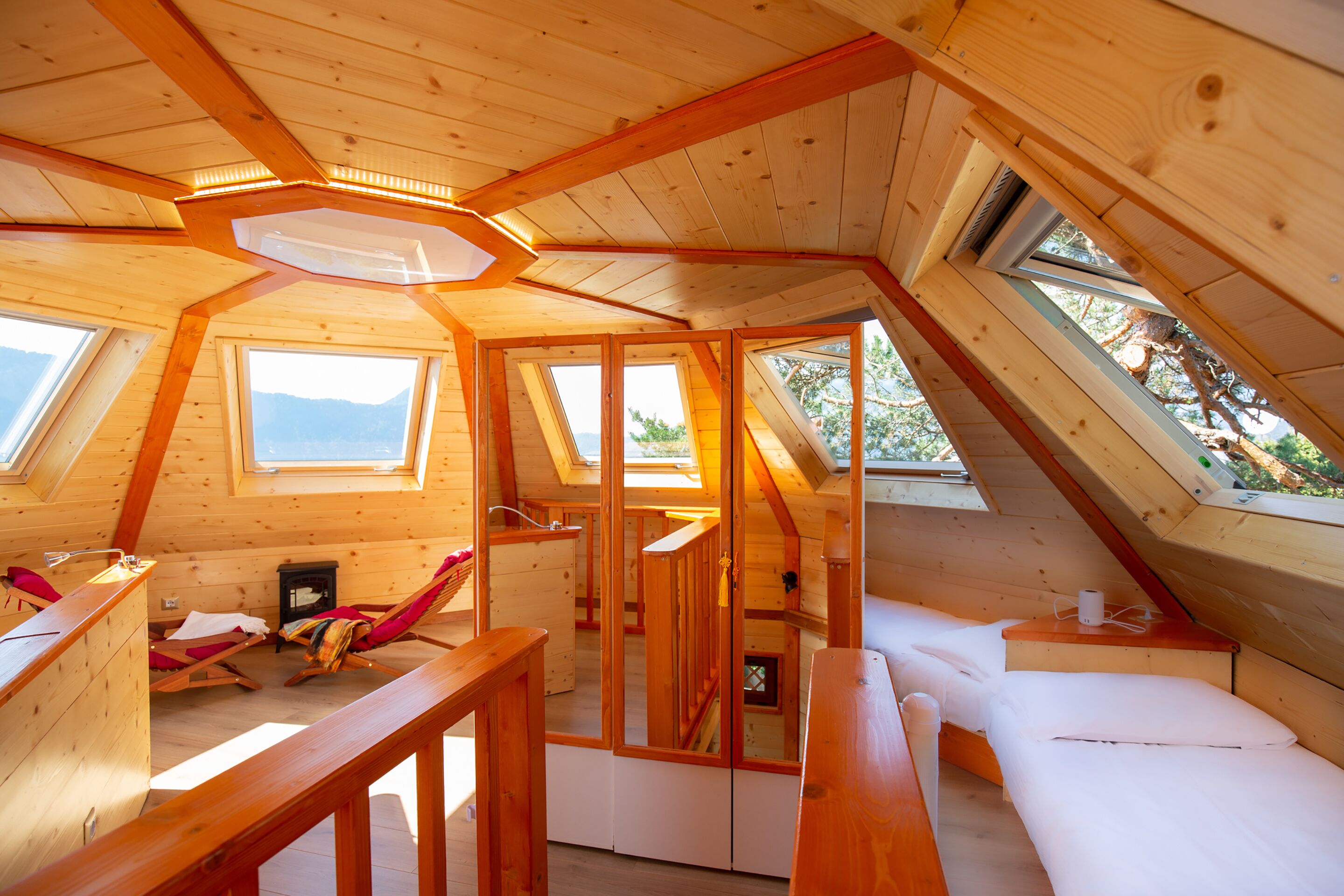 Ein gemütliches Schlafzimmer im Dachgeschoss mit Holzbalken, einem Oberlicht, einem Bett und einem kleinen Schreibtisch.