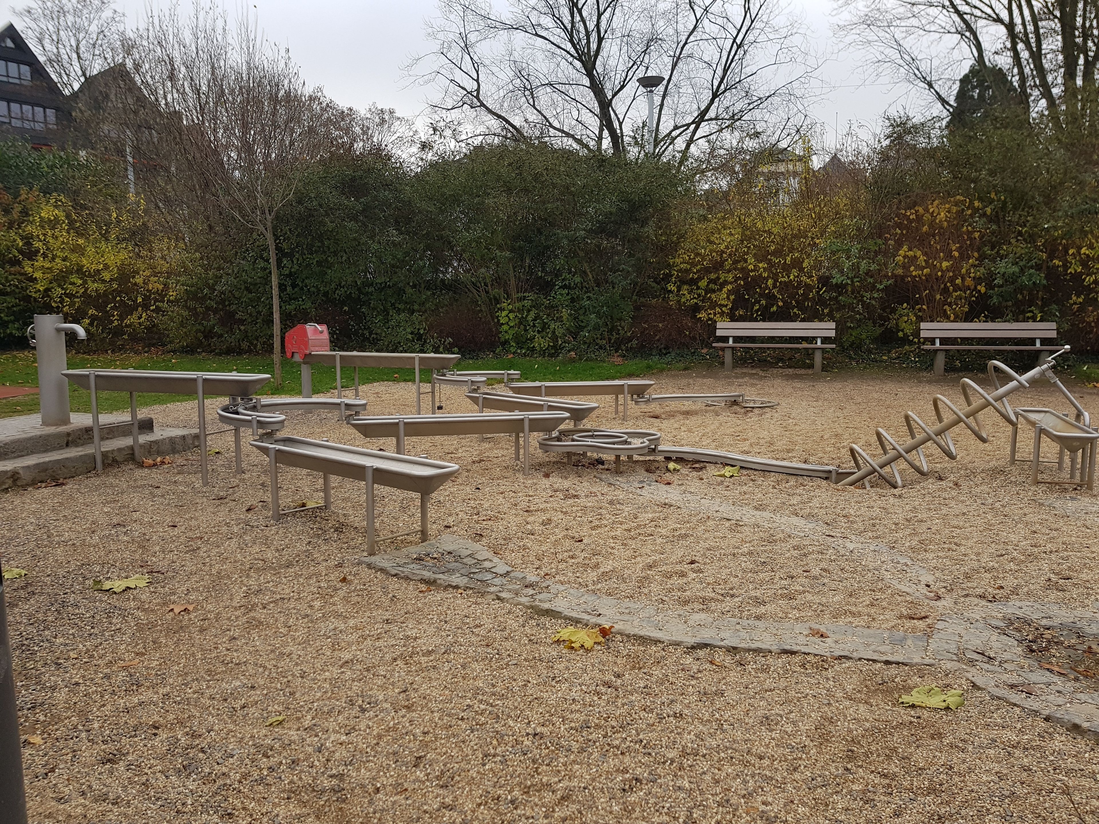 Ein Park mit Fitnessgeräten, Bänken und einem Spielplatz.