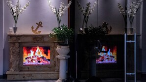 Ein Kamin mit Feuer, umgeben von Topfpflanzen und Dekorationselementen.