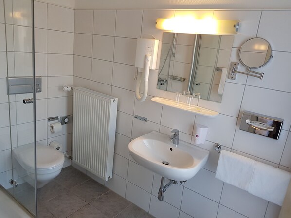 Un baño moderno con inodoro, lavamanos y espejo.