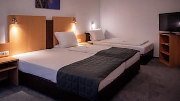 Ein Hotelzimmer mit zwei Betten, einem Fernseher und einem Bild an der Wand.